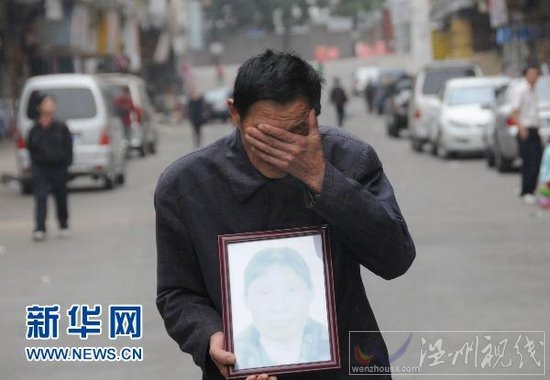 4月5日，在廣東省東莞市鳳崗鎮，肖國海捧著妻子吳喜英的遺像掩面哭泣。