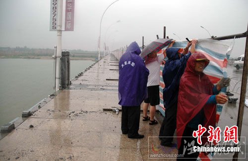 圖為大風(fēng)吹垮的橋欄已被清理，工人們在冒雨加裝圍擋。