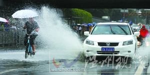 閃 潘家園橋下，汽車掀起的積水飛濺到騎自行車人的身上。本報(bào)記者 尹亞飛 攝