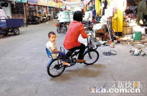 佛山五金市場，一位母親帶著孩子騎車路過事發地點。
