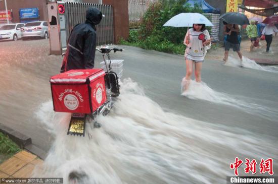 2012年7月21日，北京普降暴雨，朝陽區北部立水橋南地區積水嚴重。一小區門口，積水沿斜坡形成巨大水流，阻礙人們通行。圖片來源：CFP視覺中國